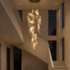 Auretta gold sculptural LED chandelier illuminating a modern stairwell
