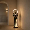 Humano Mirror matte black sculptural floor lamp illuminating a modern hallway