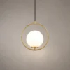 Abree modern gold pendant light featuring an illuminated white glass globe within a circular metal frame