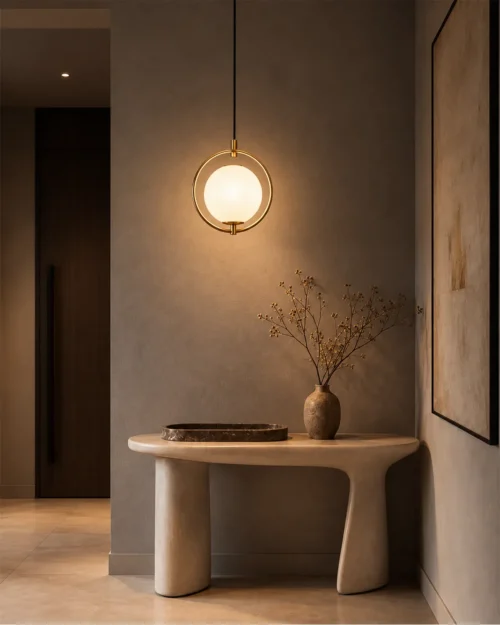 Abree decorative gold pendant light with a glowing white glass globe above a modern console table