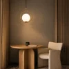 Abree gold circular pendant light suspended above a round wooden table in a contemporary dining area
