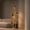 Aion sculptural pendant light with three angled shades beside a modern upholstered sofa