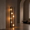 Alister brushed black floor lamp featuring six illuminated glass spheres beside an arched doorway