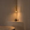 Amalea Gold Pendant Light Modern Interior Amalea slim gold pendant light providing warm downward illumination above a minimalist interior shelf