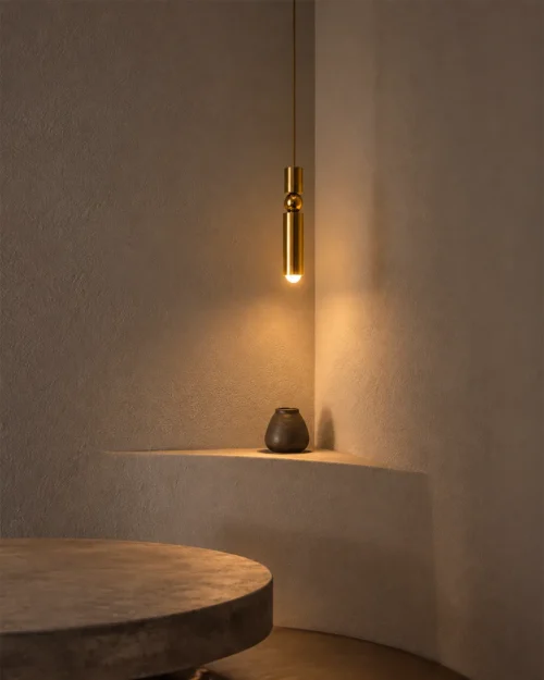 Amalea Gold Pendant Light Modern Interior Amalea slim gold pendant light providing warm downward illumination above a minimalist interior shelf