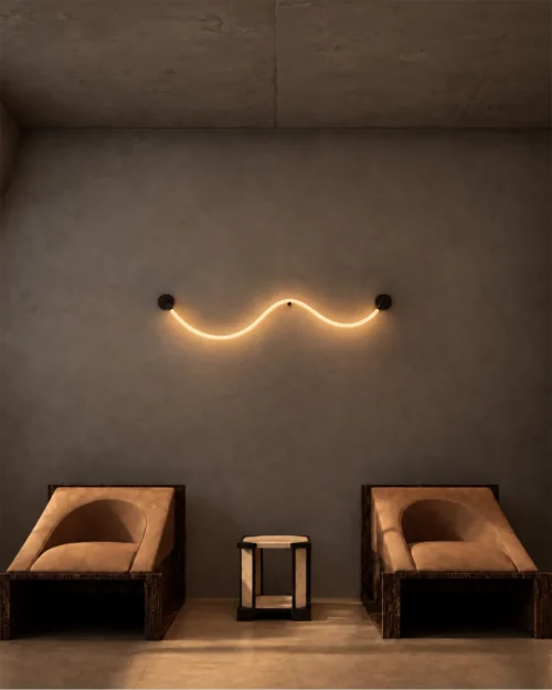 Archer wave-inspired wall lamp illuminating a contemporary seating area with two lounge chairs