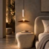 Asteria Gold pendant light suspended beside an upholstered bed and stone bedside table