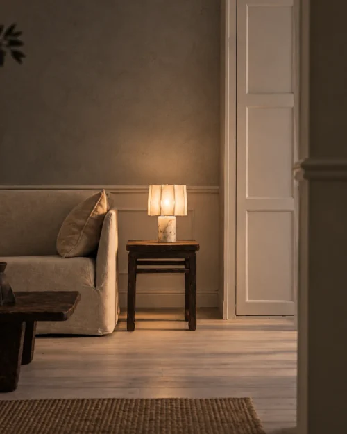 Astra Table Lamp Modern Bedroom Astra table lamp with a softly illuminated pleated shade on a bedside table beside a contemporary bed