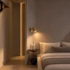 Aurelio Gold Wall Lamp Modern Bedroom Aurelio gold wall spotlight providing warm illumination beside a bed in a contemporary bedroom