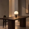 Avorio table lamp with illuminated dome shade on a dark wooden dining table