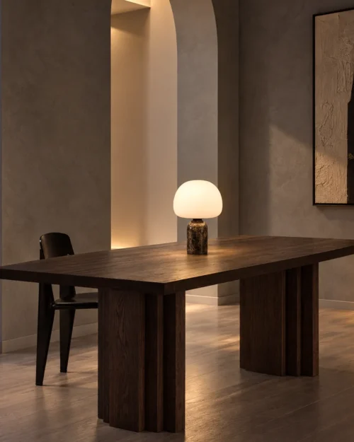 Avorio table lamp with illuminated dome shade on a dark wooden dining table