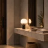 Avorio table lamp displayed on a stone console beneath a wall mirror