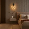 Ayla sculptural wall lamp with overlapping illuminated rings mounted beside a bed in a modern bedroom