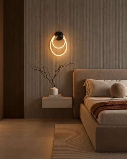 Ayla sculptural wall lamp with overlapping illuminated rings mounted beside a bed in a modern bedroom