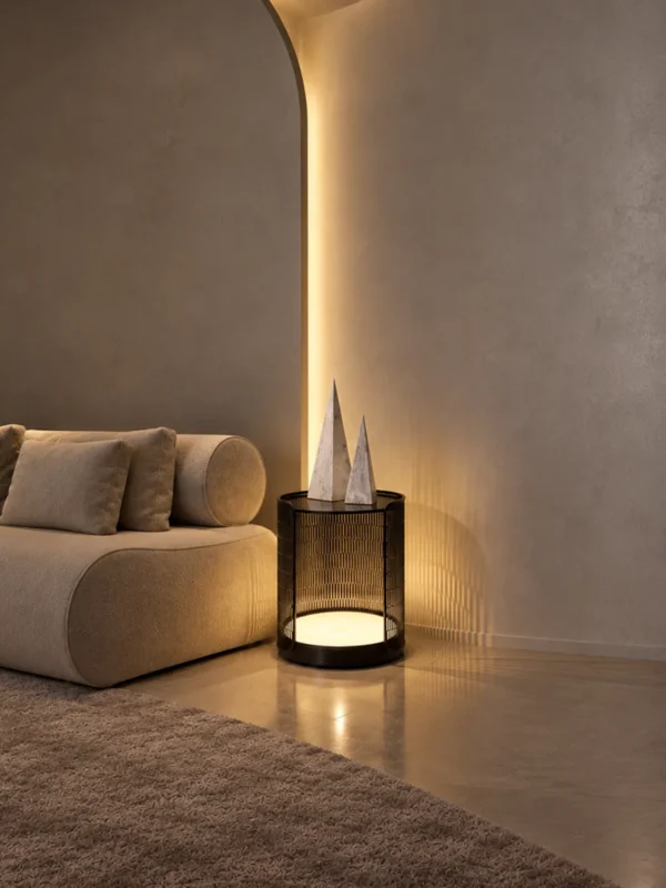 Bellora cylindrical table lamp with Coffee Black finish beside a curved sofa in a modern interior