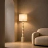 Bianca white sculptural floor lamp beside a curved sofa in a warm contemporary living room