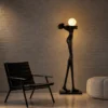 Civil Love black human-inspired floor lamp with spherical lighting beside a modern accent chair