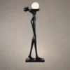 Civil Love black sculptural floor lamp featuring an elongated human figure holding a glowing spherical light