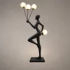 Humano Aria Sculptural Floor Lamp Humano Aria black sculptural floor lamp with a balancing human figure and four illuminated white globes