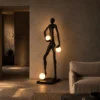 Humano Atlas black human-inspired floor lamp with illuminated globes beside a modern sofa