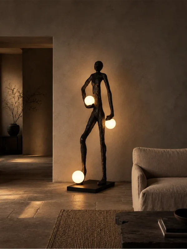 Humano Atlas black human-inspired floor lamp with illuminated globes beside a modern sofa