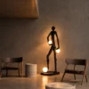 Humano Atlas sculptural floor lamp with three glowing spheres displayed in a contemporary interior with lounge chairs