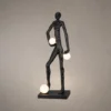 Humano Atlas black sculptural floor lamp featuring a walking human figure carrying three illuminated white globes