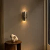Martina architectural wall lamp with reflective chrome panels mounted above a wooden console table