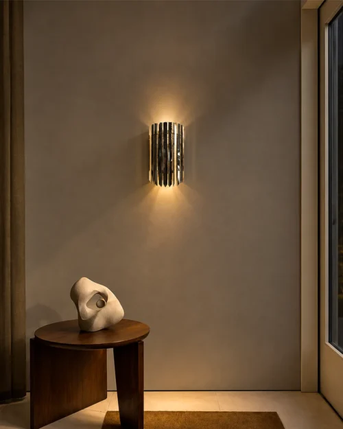 Martina architectural wall lamp with reflective chrome panels mounted above a wooden console table