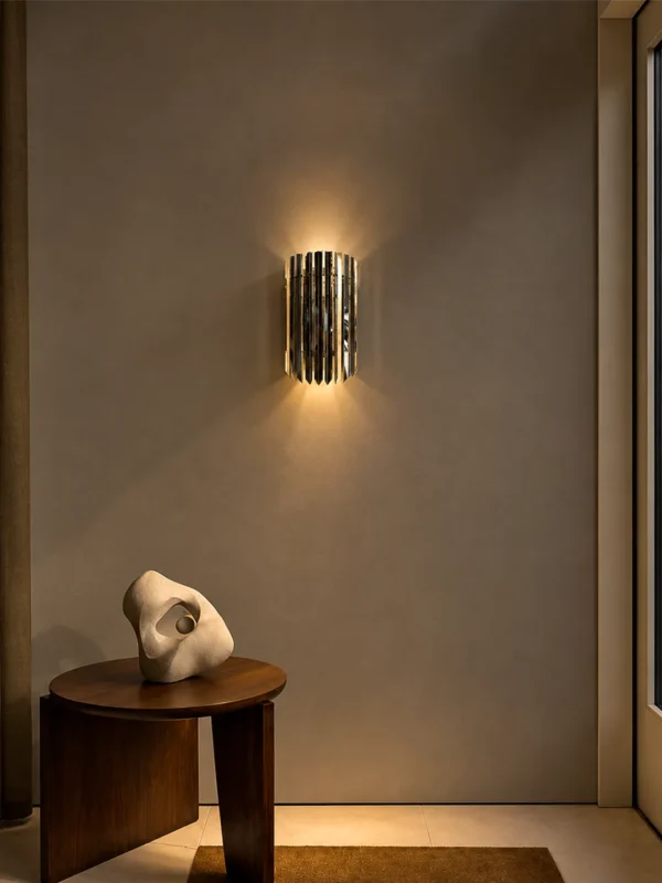 Martina architectural wall lamp with reflective chrome panels mounted above a wooden console table