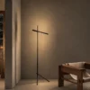 Mithra Floor Lamp Contemporary Interior Mithra linear floor lamp with black finish positioned beside a wooden bench in a modern interior