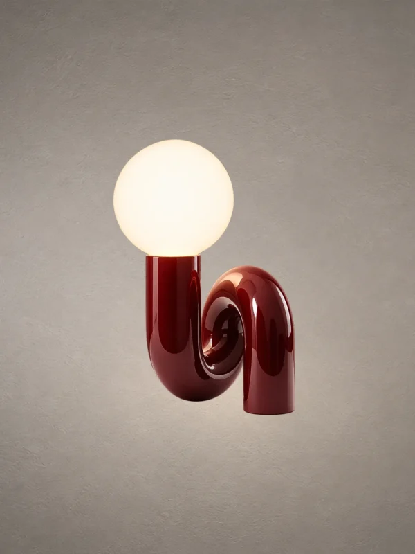 Noelle modern maroon table lamp featuring a glowing spherical glass shade and curved resin base