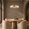 Nova Chandelier Contemporary Dining Interior Nova illuminated ring chandelier above a round dining table with upholstered chairs