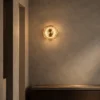 Single Orbe circular wall lamp illuminating a textured wall above a wooden console