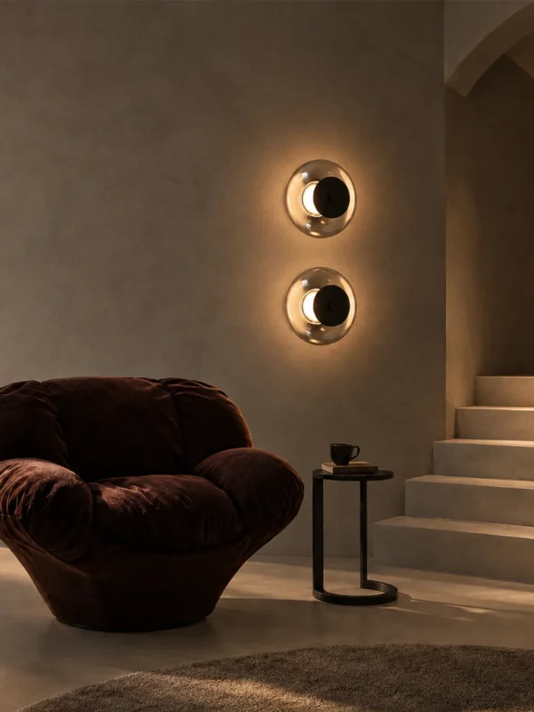 Two Orbe circular wall lamps mounted vertically beside a lounge chair in a modern interior