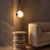 Orbit black triangular pendant light with an illuminated white globe above a sculptural side table