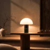 Orly green table lamp with a glowing white dome-shaped shade on a wooden console table