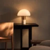 Orly table lamp with a white glass dome and gold accents illuminating a modern interior