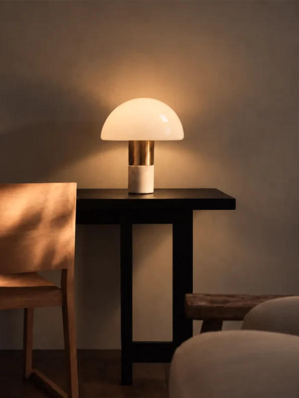 Orly table lamp with a white glass dome and gold accents illuminating a modern interior