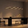 Palma linear chandelier with flowing illuminated curves above a modern dining table