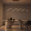 Palma wave-shaped LED chandelier suspended above a sculptural dining table