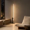 Perun vertical floor lamp beside a low upholstered lounge chair in a contemporary living room