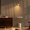 Radisson gold floor lamp with a white marble base beside a wooden cabinet in a contemporary interior