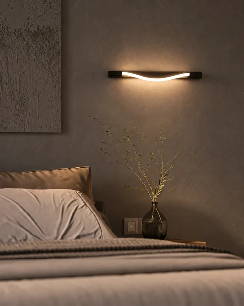Razel linear wall lamp mounted horizontally above a bed in a contemporary bedroom